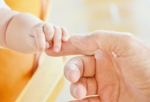 Bébé tenant la main d’un adulte – congé supplémentaire de naissance