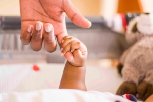 Main d’un bébé tenant le doigt de son parent