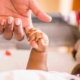 Main d’un bébé tenant le doigt de son parent